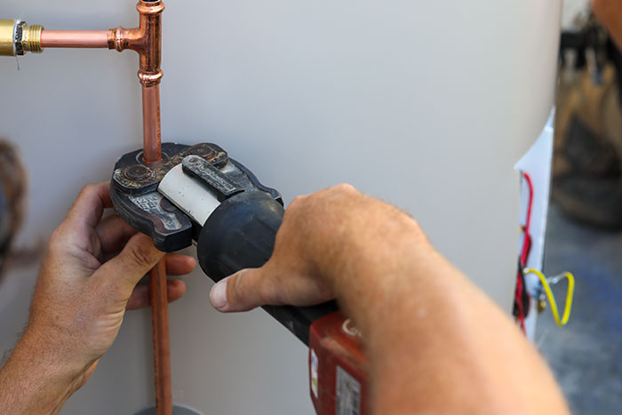Plumber securing copper pipes on a hot water system in Caboolture